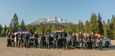 Mt. Shasta Police group photo in front of three police vehicles, Mt. Shasta towering in the distant background.